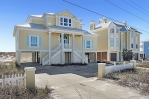 A two-story house with a front porch, a staircase, and a white picket fence. - Del Sol Beach House | Rare Dog Friendly Beachfront Home | My Beach Getaways (Gulf Shores)