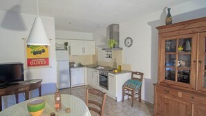 Cocina compacta con armarios blancos, horno integrado y comedor con mesa y sillas.