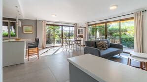 A spacious living area with a sofa, a dining table, and a kitchen counter. - Apartamentos Ponent MHM (Cala Ratjada)