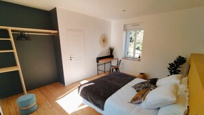 Un dormitorio con cama, escritorio, ventana y escalera.