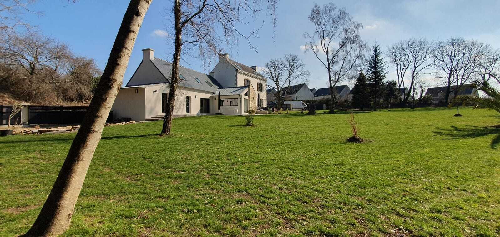 Une grande maison de plain-pied, dotée d’une pelouse bien entretenue et de plusieurs arbres.
