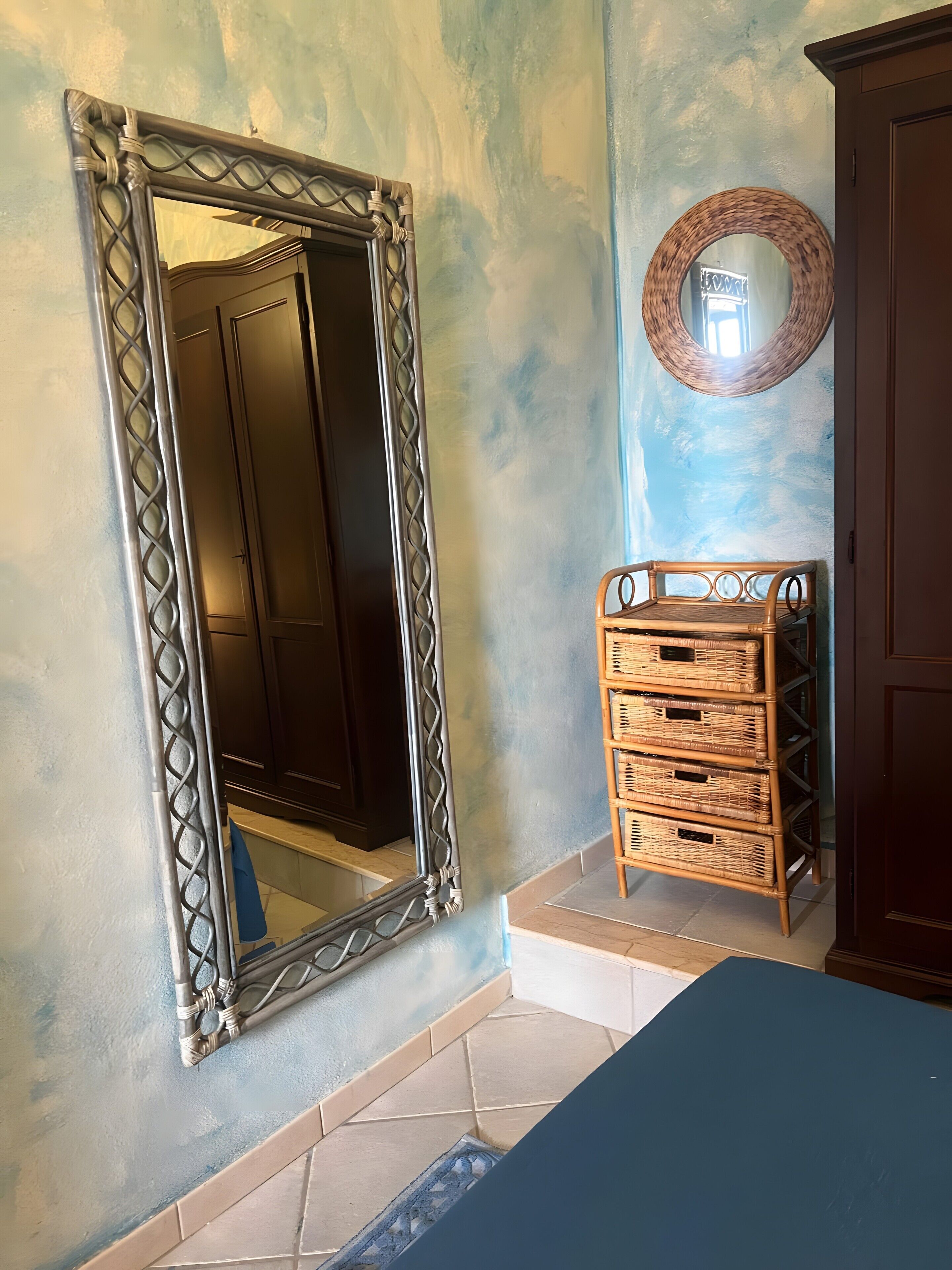 Una habitación con un espejo grande, una cesta de mimbre y un mueble de madera.