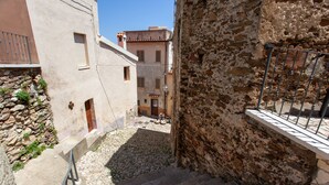 A narrow alleyway with stone steps leading to a building with a stone facade and a metal railing.
