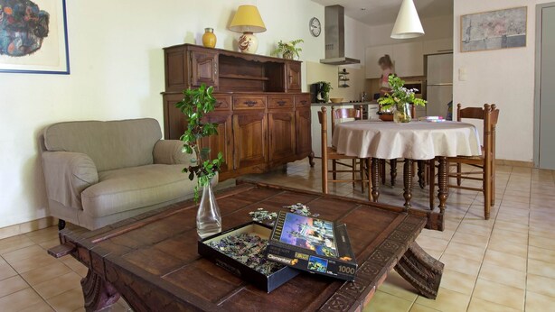 A living room with a wooden coffee table, a sofa, a dining table with chairs, and a kitchen in the background.