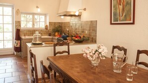 A kitchen with a dining table, chairs, a window, and a tiled backsplash. - Maison du Néflier (N°2) (Marcorignan)