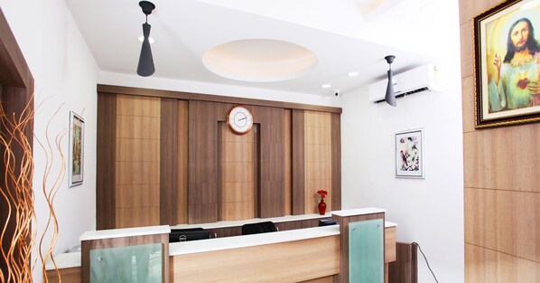 Un mostrador de recepción con un reloj, paneles de madera y un cuadro enmarcados con motivos religiosos.