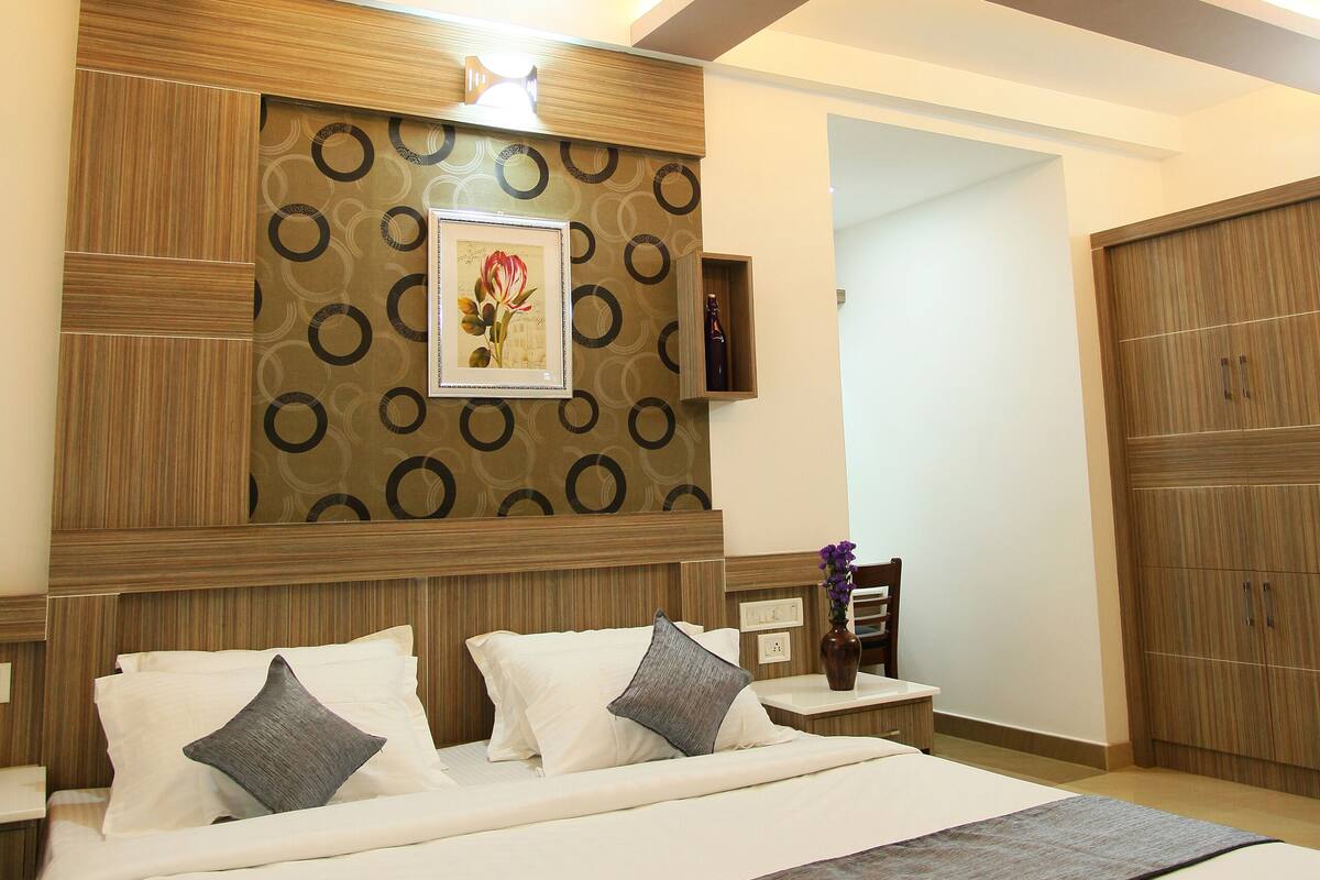 A bedroom with a large bed, a ceiling fan, and a wall-mounted TV.