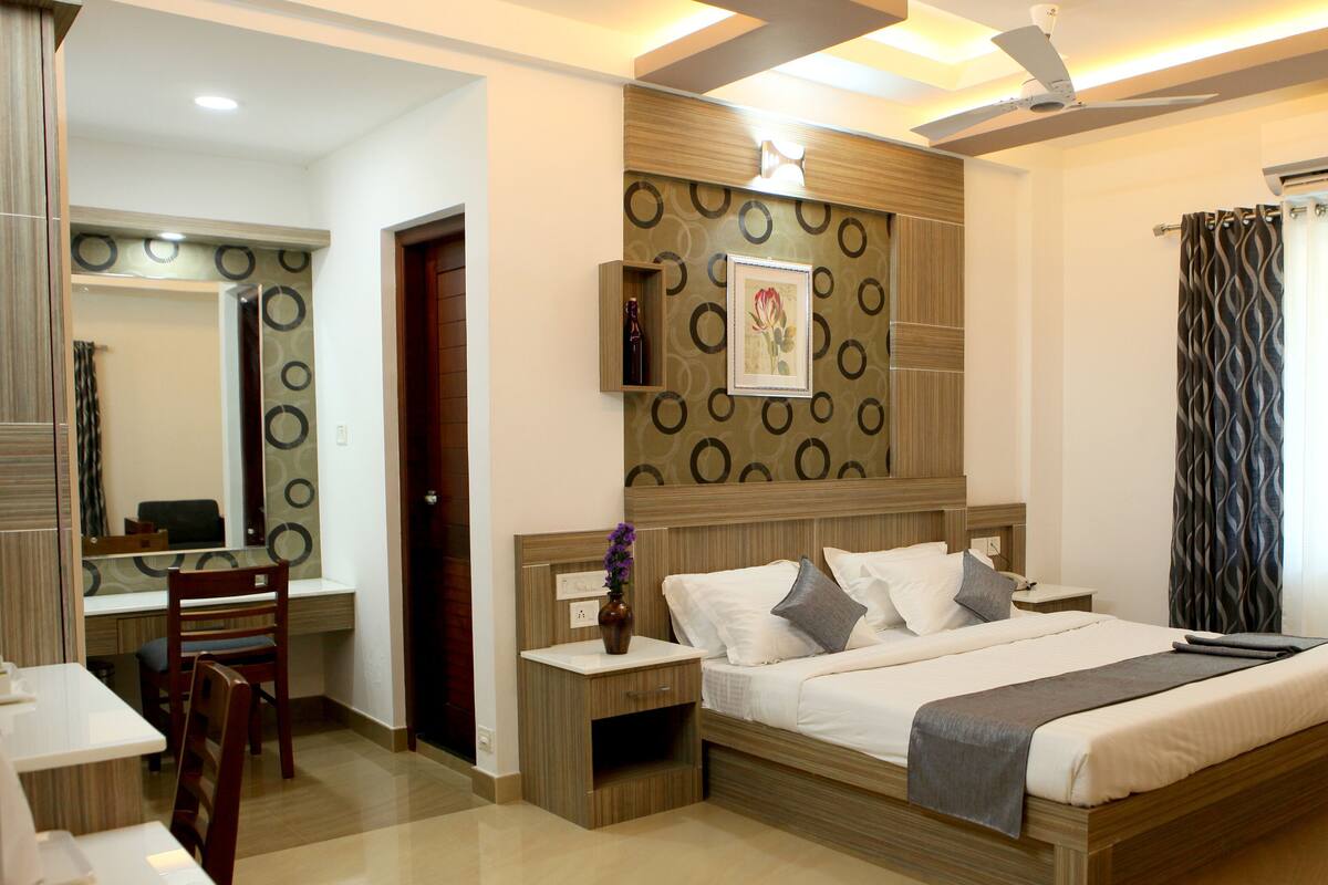 A modern hotel room with a large bed, bedside tables, a desk, and a chair.
