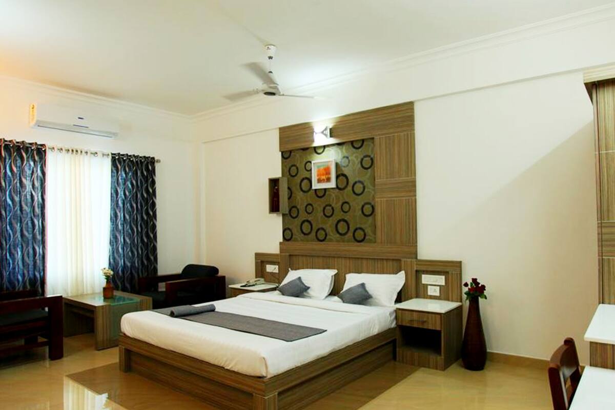 A hotel room with a large bed, bedside tables, a desk, and a chair.