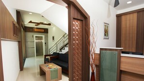 A modern hotel lobby with a staircase, a reception desk, and a seating area.