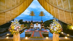 A romantic outdoor dining setup with a bamboo arch, a table with chairs, and flower arrangements. - Weda Cita Resort And Spa (Ubud)