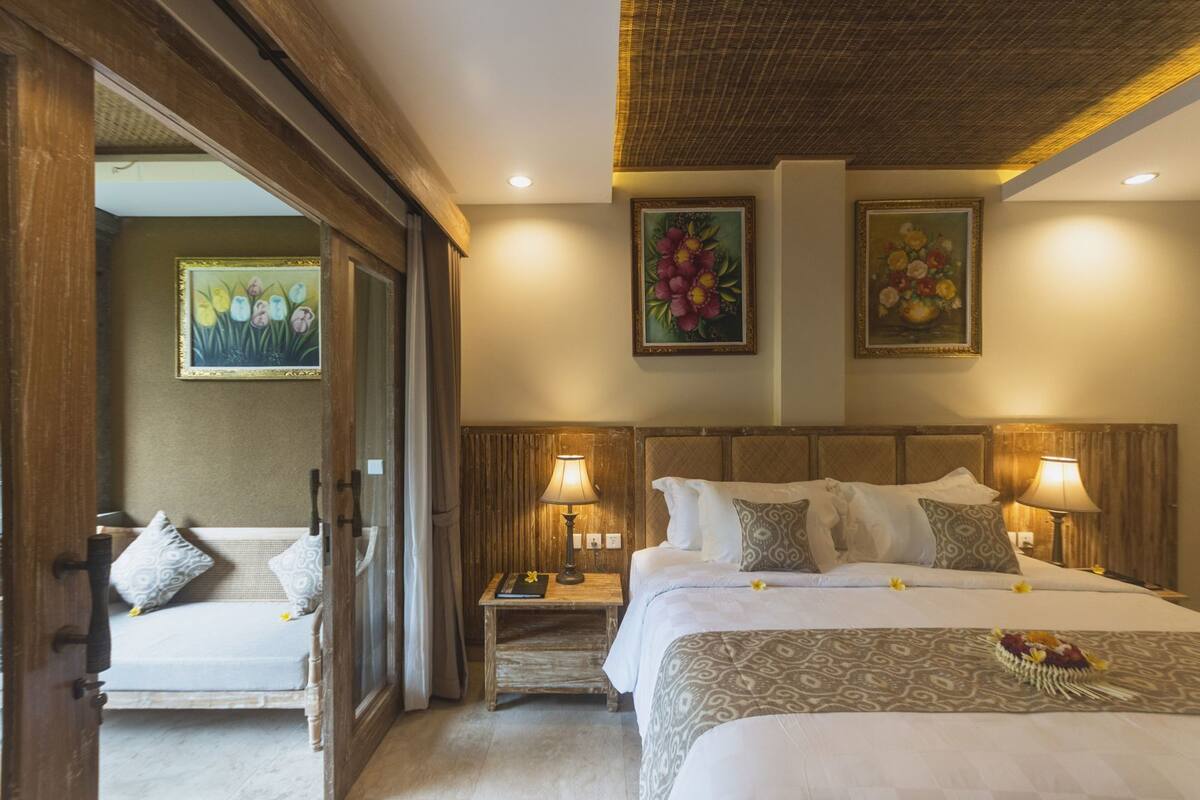 Una habitación de hotel con una cama, mesitas de noche, lámparas y dos cuadros en la pared.