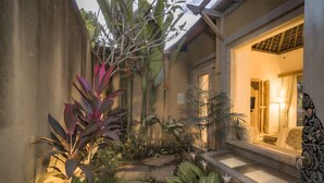 A well-maintained garden with a stone pathway leading to a door. - Weda Cita Resort And Spa (Ubud)