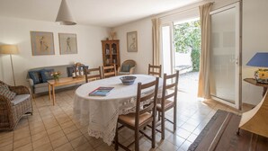 A dining area with a round table, chairs, a sofa, and a cabinet. - Maison du Prunier (N°5) (Marcorignan)