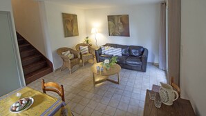 A living room with a sofa, coffee table, and dining table with eggs and vegetables. - Maison de l'Amandier (N°9) (Marcorignan)