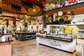 A buffet area with a counter labeled "Gosztland Bistrzod" and a menu board above it.