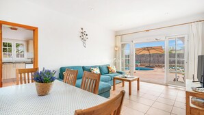 A spacious living room with a sofa, a dining table, and a TV. - Beach Resort Villa with Private Pool and Air-conditioning (Cala en Porter, Alaior)