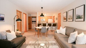 Espai habitable compacte amb sofà, taula de dinar i zona de cuina.