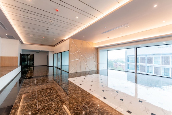A modern interior with a polished marble floor, geometric wall panels, and large windows offering a view of the city.