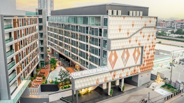 A modern hotel with multiple floors, a central courtyard, and a prominent entrance with a sign.