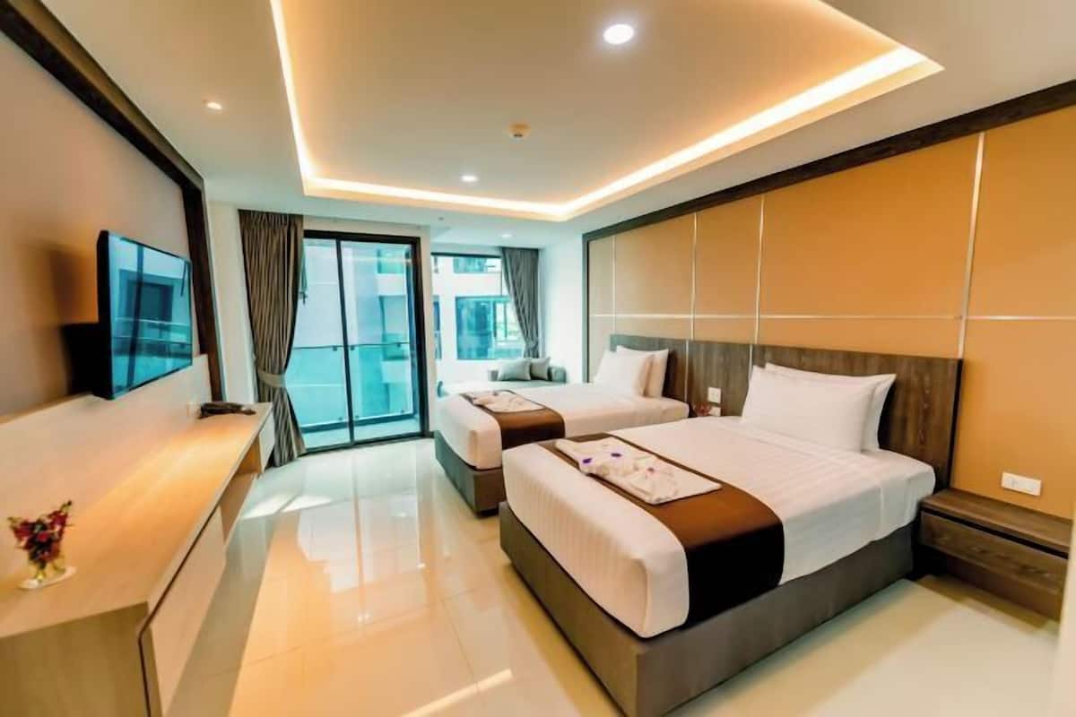 A modern hotel room with two beds, a flat-screen TV, a desk, and a balcony with curtains.