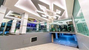 A modern interior with geometric ceiling designs, glass railings, and a central decorative light fixture.