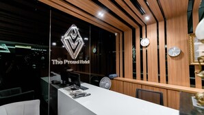 A reception desk with a modern design, featuring a logo, a clock, and a fan.