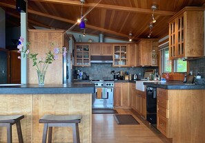 A modern kitchen with wooden cabinets, a central island, and a built-in oven.