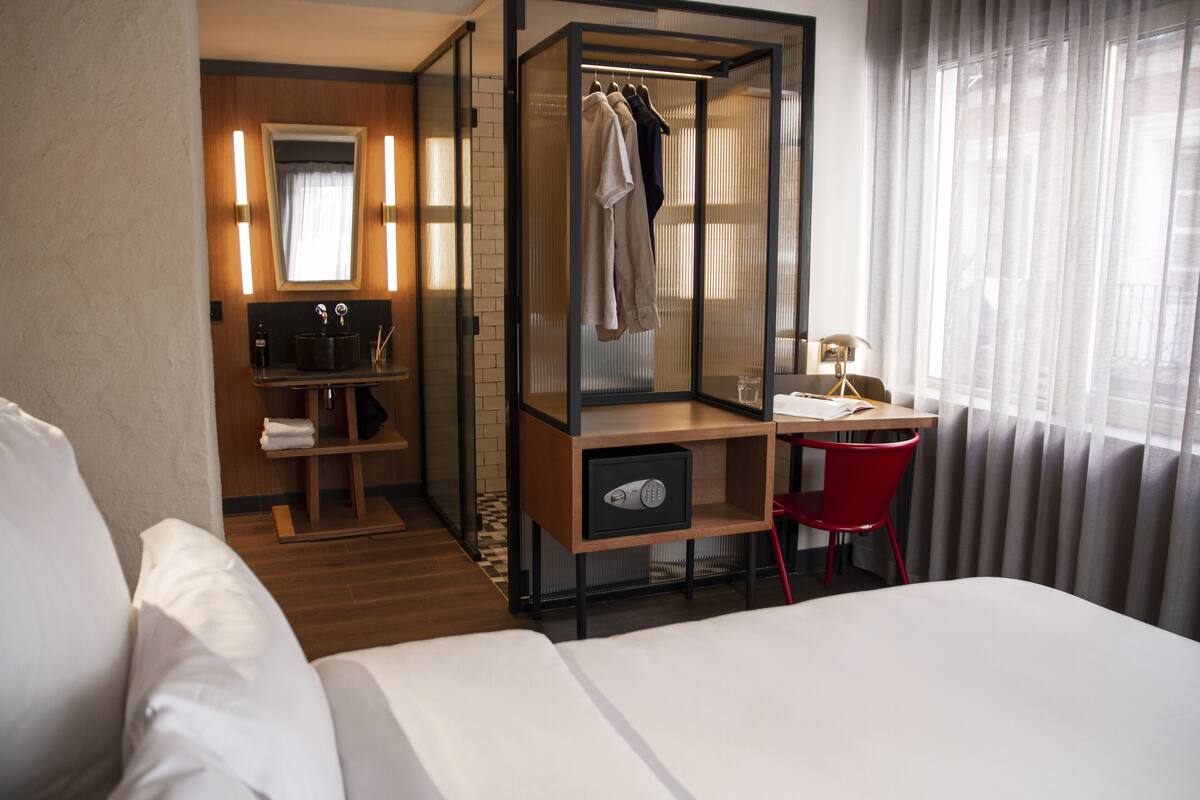 Une chambre d’hôtel comprenant un lit, un bureau avec une chaise, une armoire et un miroir.