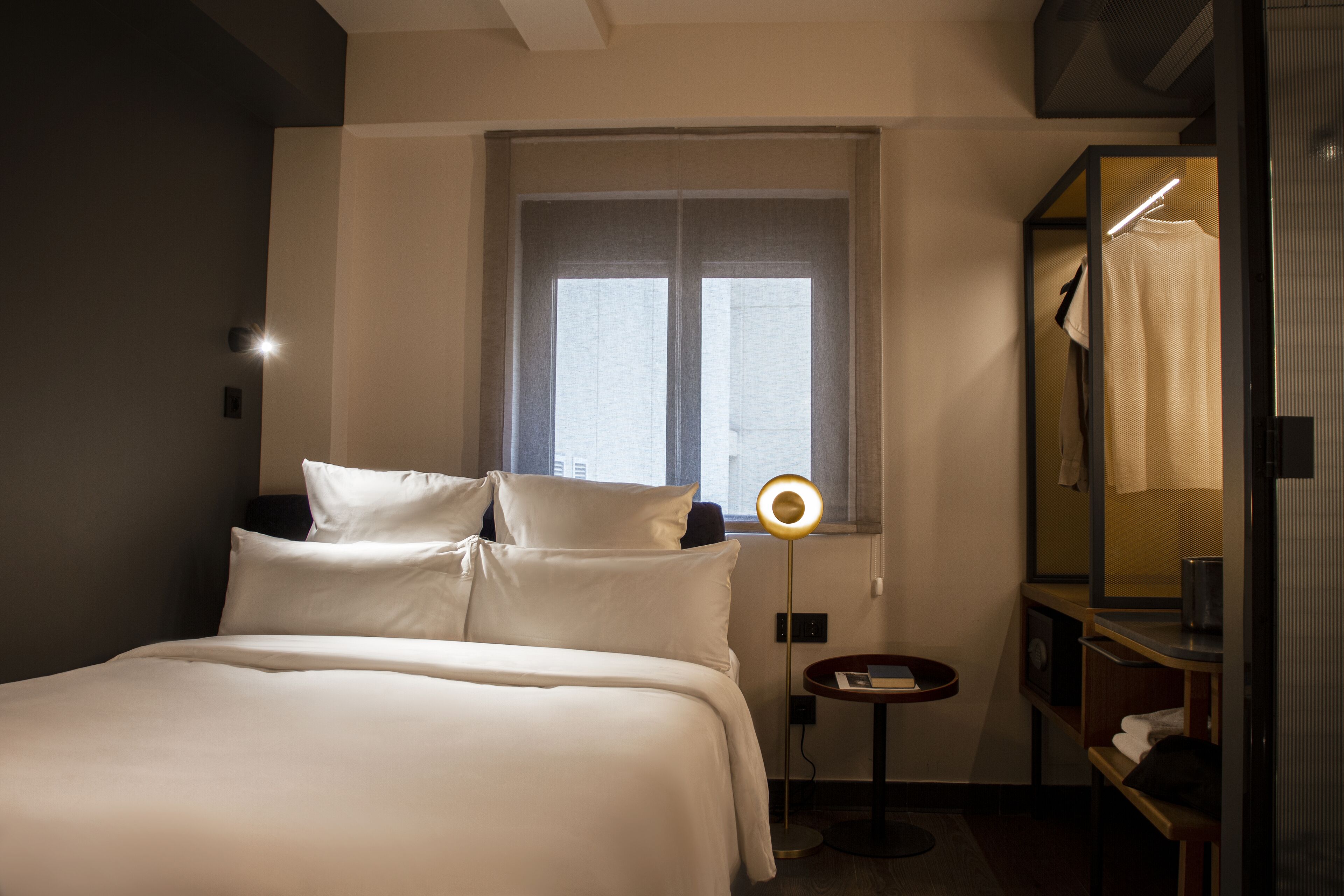Une chambre d’hôtel avec un lit, une table de chevet, un miroir et une fenêtre.