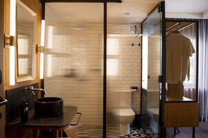 A bathroom with a black sink, a mirror, a toilet, and a shower area.