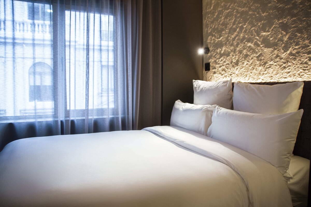 Un lit bien fait, avec du linge de lit blanc, dans une chambre d'hôtel.