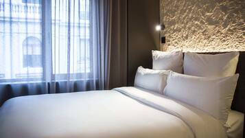 Una cama bien tendida con sábanas blancas en una habitación de hotel.