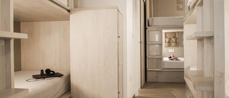 A narrow corridor with bunk beds on either side and a door at the end.