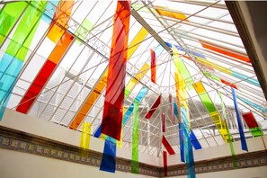 A modern interior with a glass ceiling and colorful hanging elements. - Room Salvador (Seville)