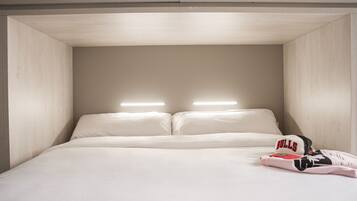 Een bed met twee kussens, een hoofdbord met geïntegreerde verlichting en een Bulls pet op het bed.