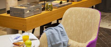 Un coin repas avec une table dressée pour deux personnes, une chaise, un plateau avec de la nourriture et des boissons, et un panneau néon au-dessus.