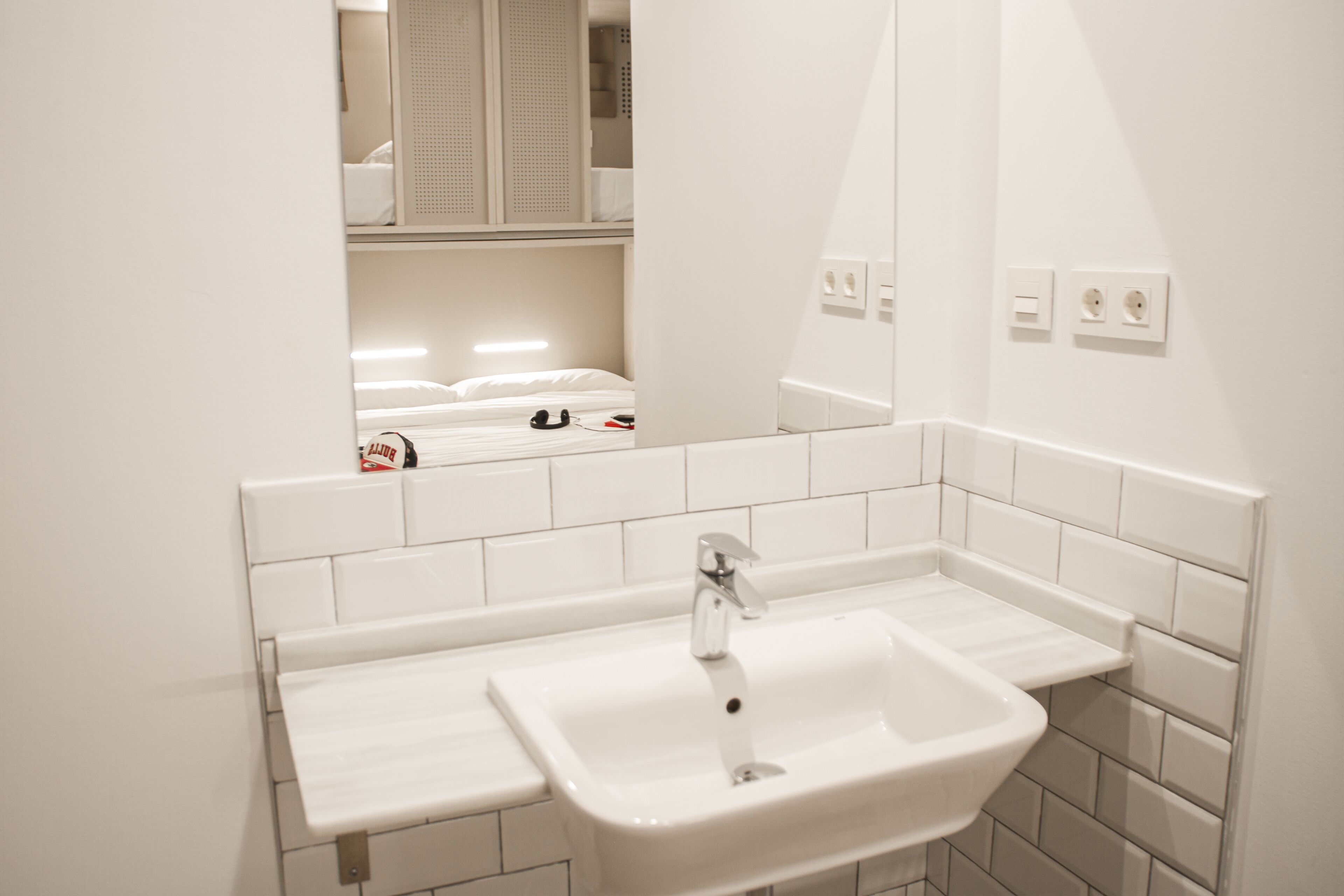 A bathroom with a white sink, mirror, and tiled walls.