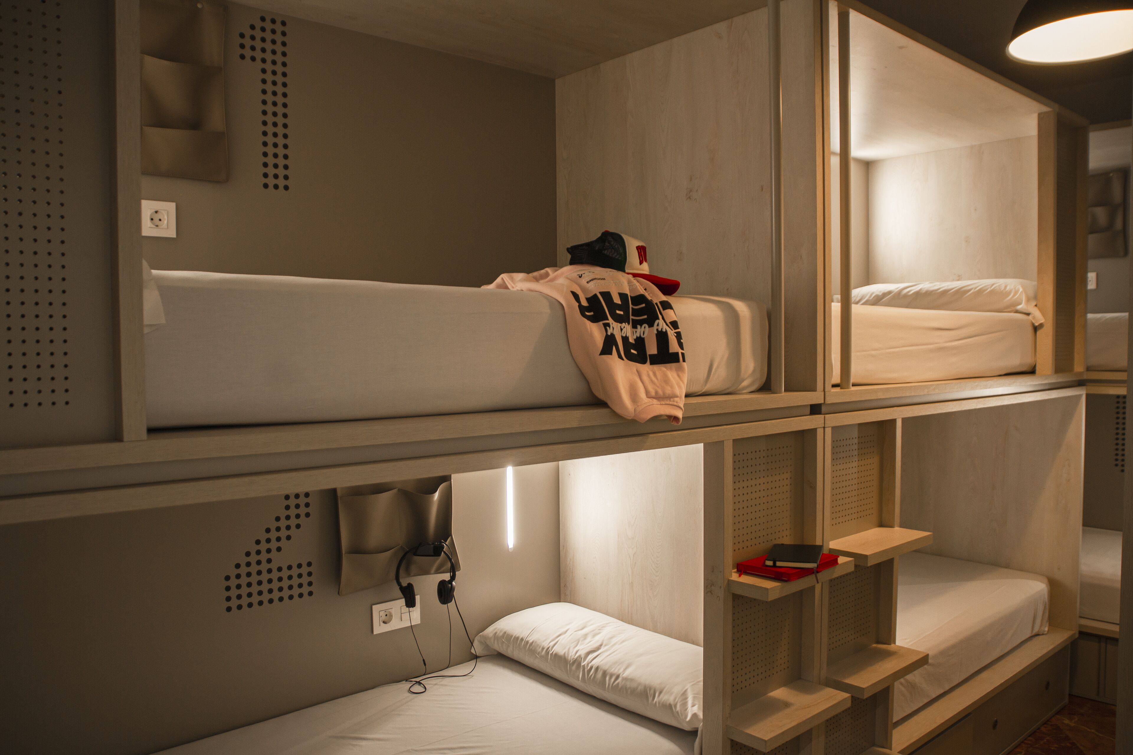 Camera con letto a castello, una scrivania, una presa di corrente e una mensola a parete.