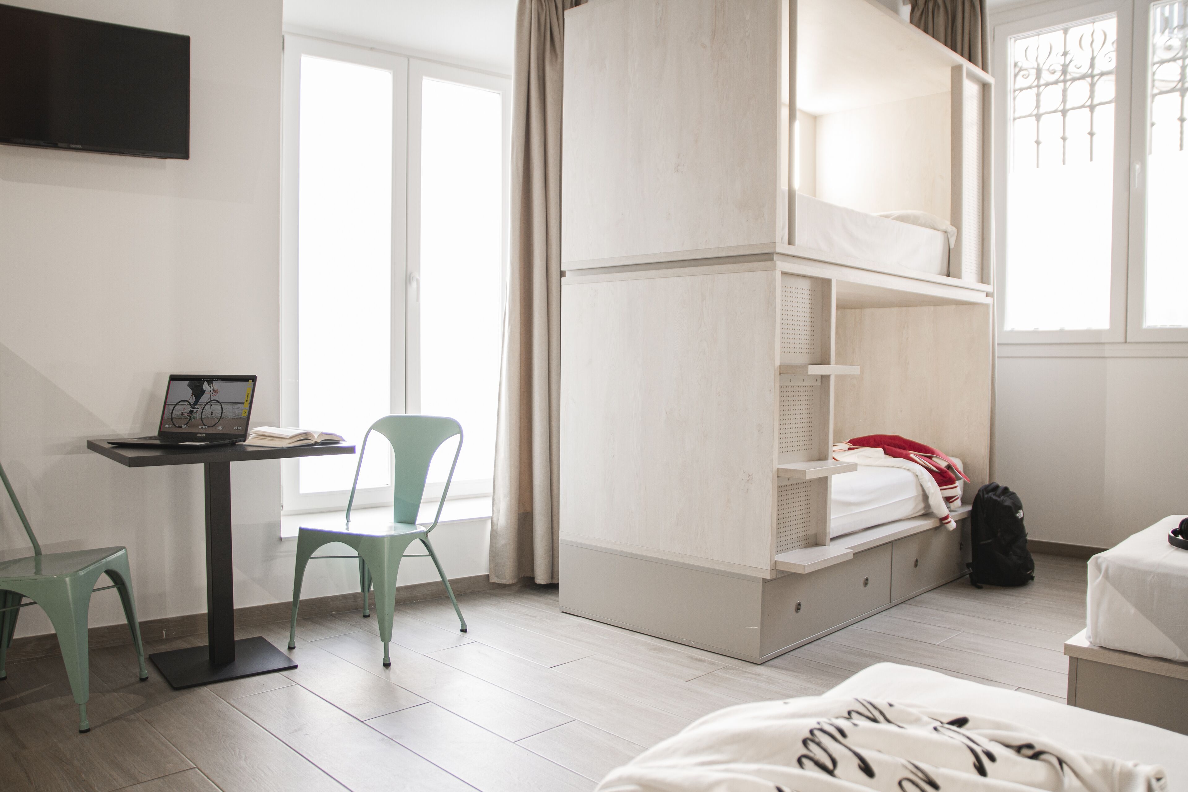 Un dormitorio con literas, un escritorio con una computadora portátil, una silla y una cama con una colcha.