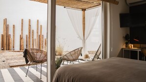 A bedroom with a bed, a chair, a TV, and a view of the outside. - Select Tetuán (Seville)