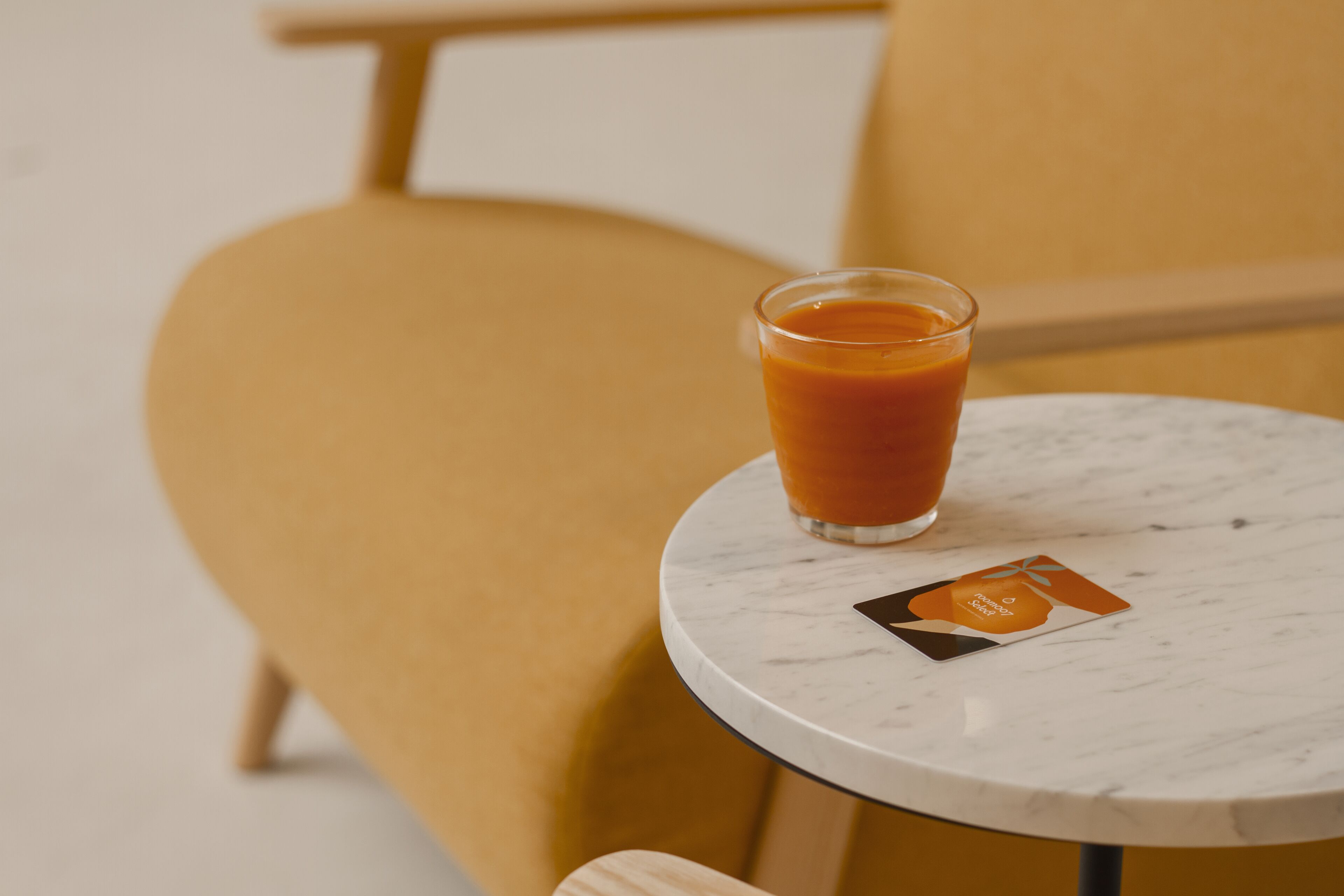 A glass of orange juice on a marble table with a business card beside it.