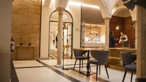 A modern interior with a reception desk, seating area, and a brick wall. - Select Tetuán (Seville)