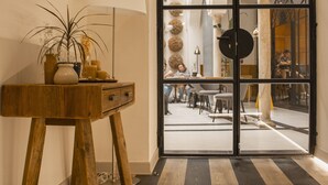 A wooden console table with a potted plant and candles, leading to a room with a large arched doorway and a view of a dining area. - Select Tetuán (Seville)