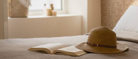 Una cama con un libro abierto y un sombrero de paja encima.