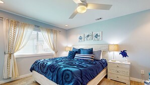 Ein Schlafzimmer mit einem Bett, Nachttischen, einem Deckenventilator und Kunstwerken an der Wand.