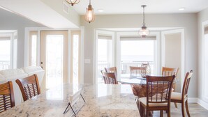 A dining area with a marble table, wooden chairs, and pendant lighting. - Herring House- Gulf front, St Joe Beach, WIFI, No pets, Sleeps 7 (Saint Joe Beach)