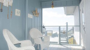A room with two white wicker chairs, a wooden wall, and a large window overlooking a deck. - Herring House- Gulf front, St Joe Beach, WIFI, No pets, Sleeps 7 (Saint Joe Beach)