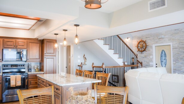 A modern kitchen with wooden cabinets, a central island, and pendant lighting. - Herring House- Gulf front, St Joe Beach, WIFI, No pets, Sleeps 7 (Saint Joe Beach)
