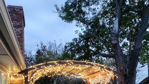Un patio couvert agrémenté de guirlandes lumineuses, d’une table et de chaises.